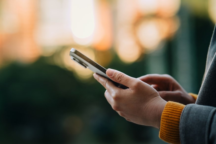 Dame holder en mobil. Nært bilde av telefonen i hånden.