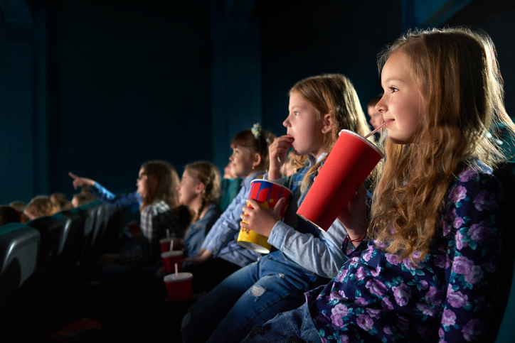 Jenter på kino smiler og koser seg med drikke.